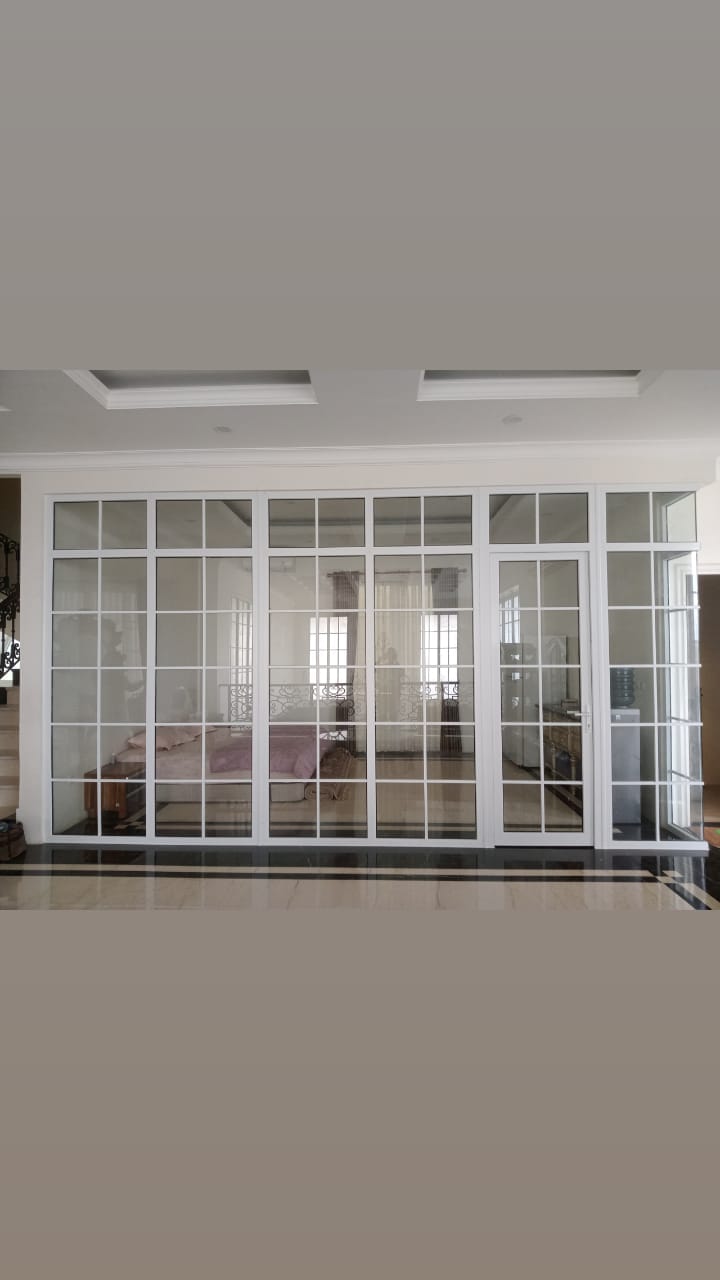 Kombinasi panel kaca tetap dan akses pintu pada ruang interior.